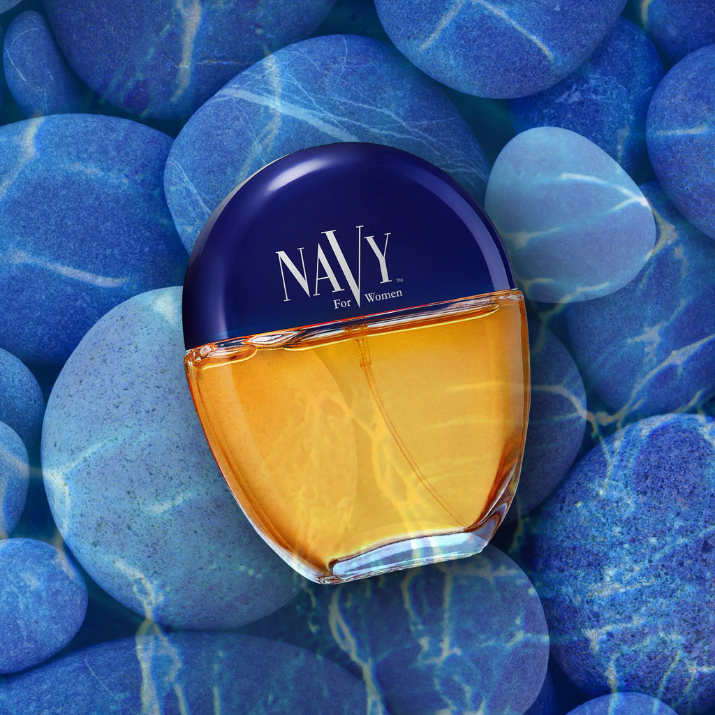 Editorial shot of a bottle of Navy For Women cologne spray under water on blue pebbles
