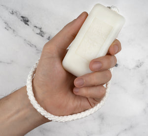 Editorial shot of a man's hand holding English Leather soap in a rope.